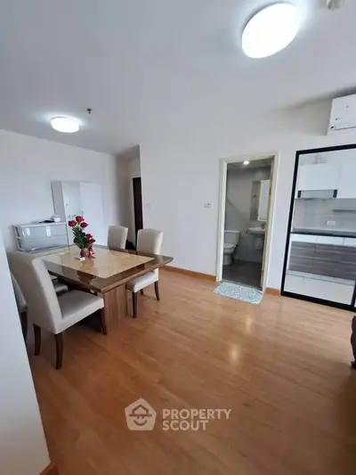 Spacious dining area with elegant wooden table and modern kitchen in open layout apartment.