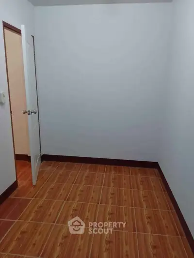 Spacious empty room with wooden flooring and open door, ideal for customization.