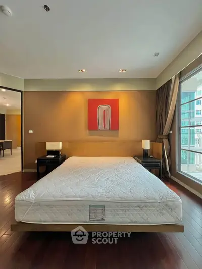 Spacious bedroom with modern decor and large window offering natural light.