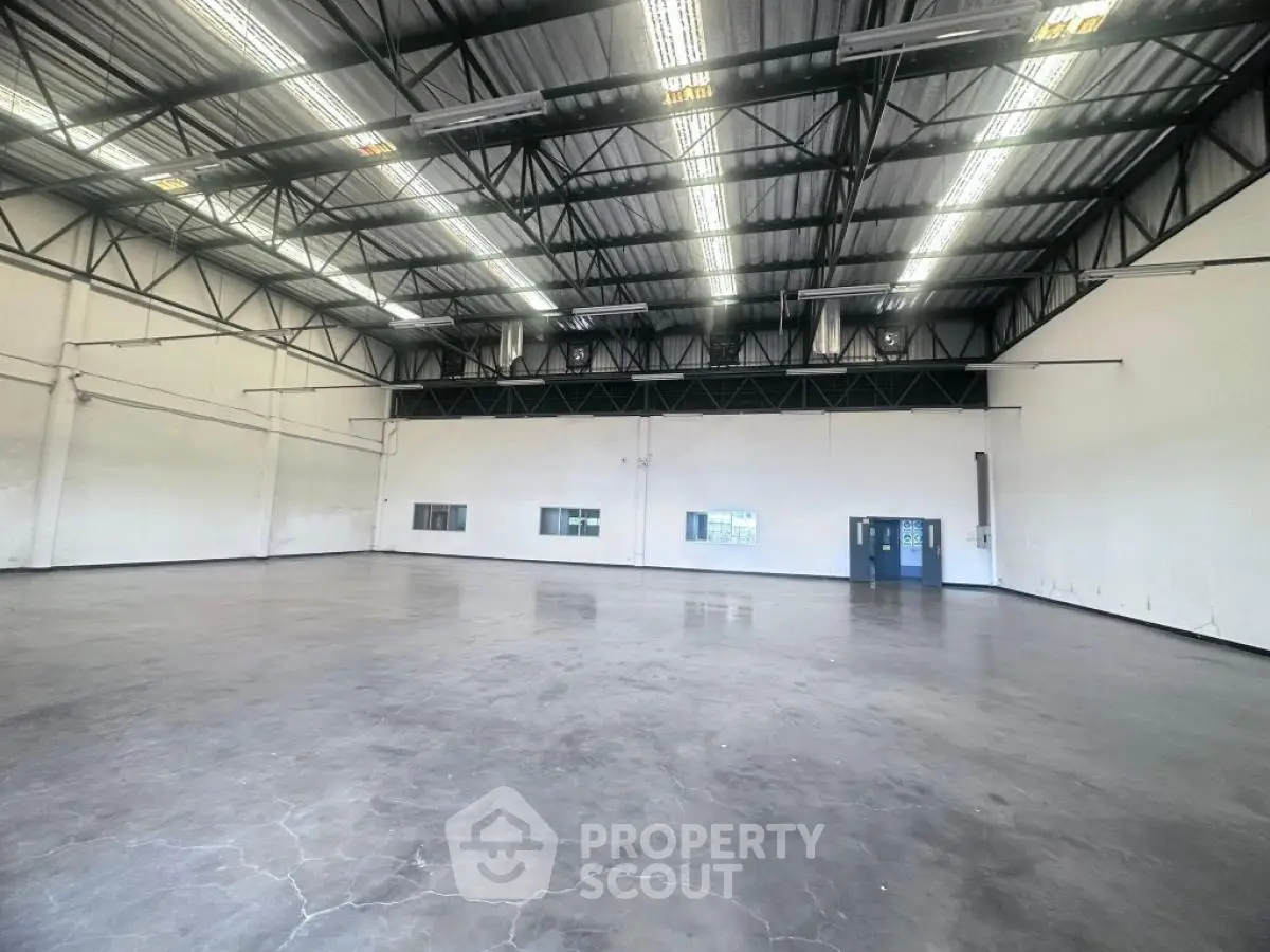 Spacious industrial warehouse with high ceilings and ample lighting.