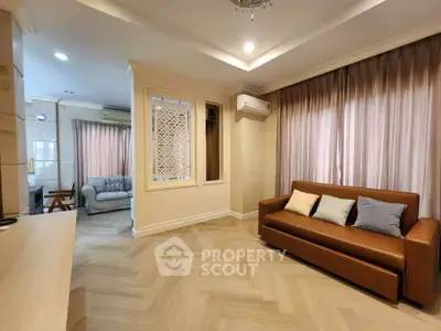 Spacious living room with elegant decor and ample natural light, featuring a cozy sofa and stylish flooring.