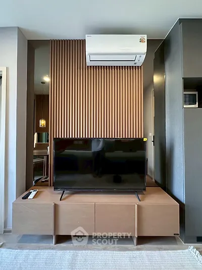 Modern living room with sleek TV setup and stylish wood paneling, featuring air conditioning for comfort.