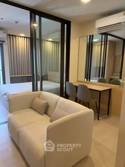 Modern living room with cozy sofa and stylish dining area in open-plan apartment.