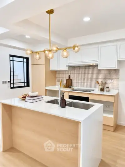 Modern kitchen with sleek island, elegant lighting, and stylish cabinetry in a contemporary home.