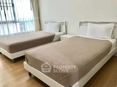 Spacious bedroom with twin beds and large window offering natural light.