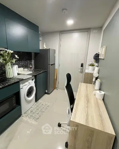 Modern compact kitchen with washing machine and sleek cabinetry in stylish apartment.