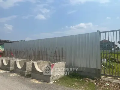 Vacant land with construction fencing and clear blue sky, ideal for development opportunities.