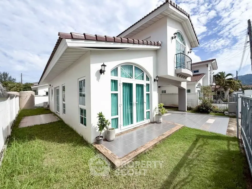 Charming two-story house with elegant arched windows and lush green lawn, perfect for family living.
