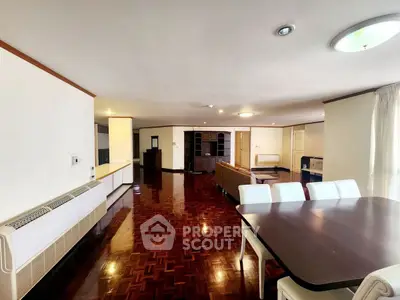 Spacious open-plan living and dining area with polished wooden floors and modern furniture.