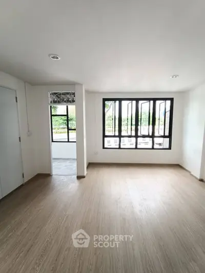 Spacious and bright living room with large windows and wooden flooring, perfect for modern living.