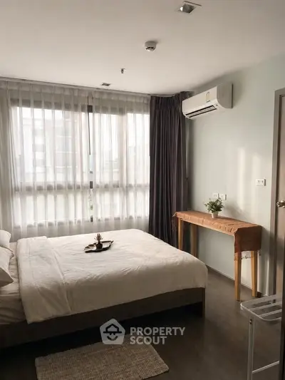 Cozy bedroom with large windows and modern decor in a stylish apartment.