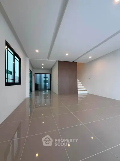 Spacious modern living room with sleek tile flooring and elegant staircase in a contemporary home.