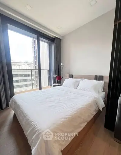 Modern bedroom with large windows and city view, featuring a cozy bed and elegant decor.