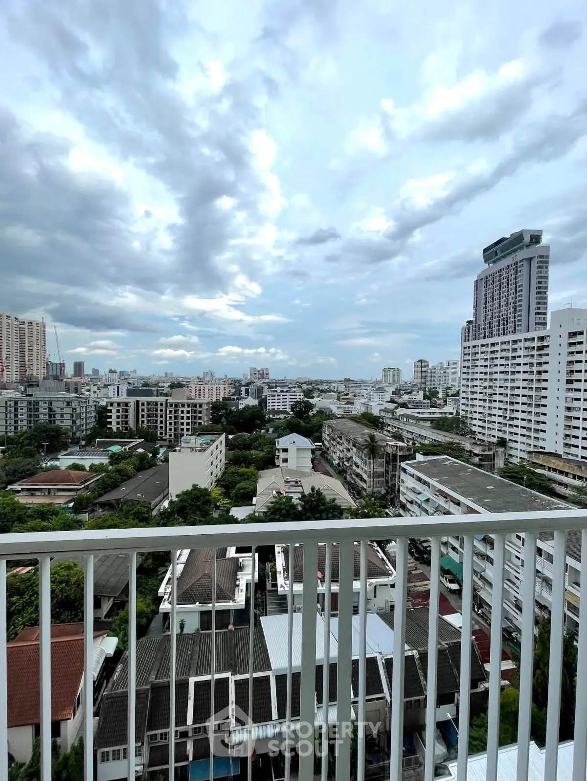 Stunning cityscape view from a high-rise balcony showcasing urban skyline and lush greenery.