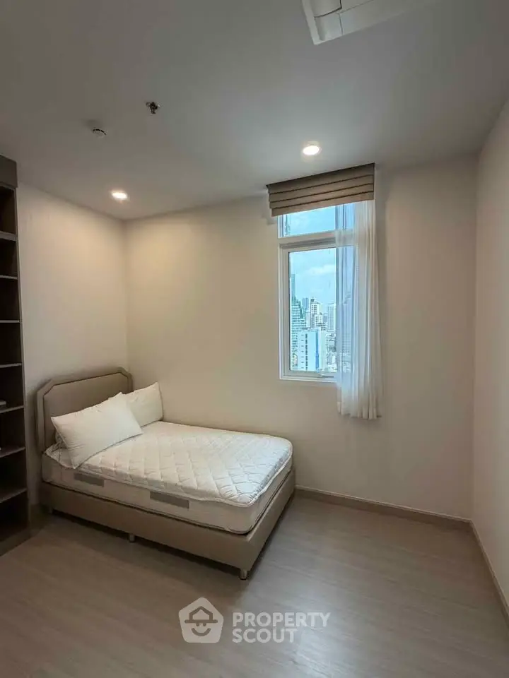 Cozy bedroom with city view, featuring a comfortable bed and ample natural light.