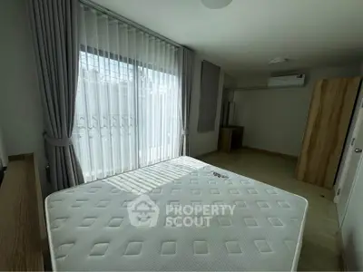 Spacious bedroom with large window and modern furnishings in a bright apartment.