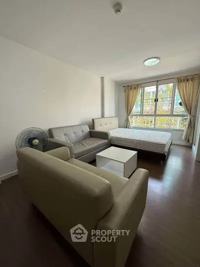 Spacious studio apartment with cozy seating and large window view