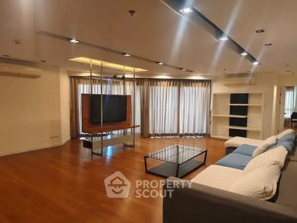 Spacious modern living room with sleek wooden flooring and stylish furniture.