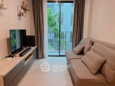 Modern living room with cozy sofa and entertainment center, featuring a view of lush greenery through large windows.