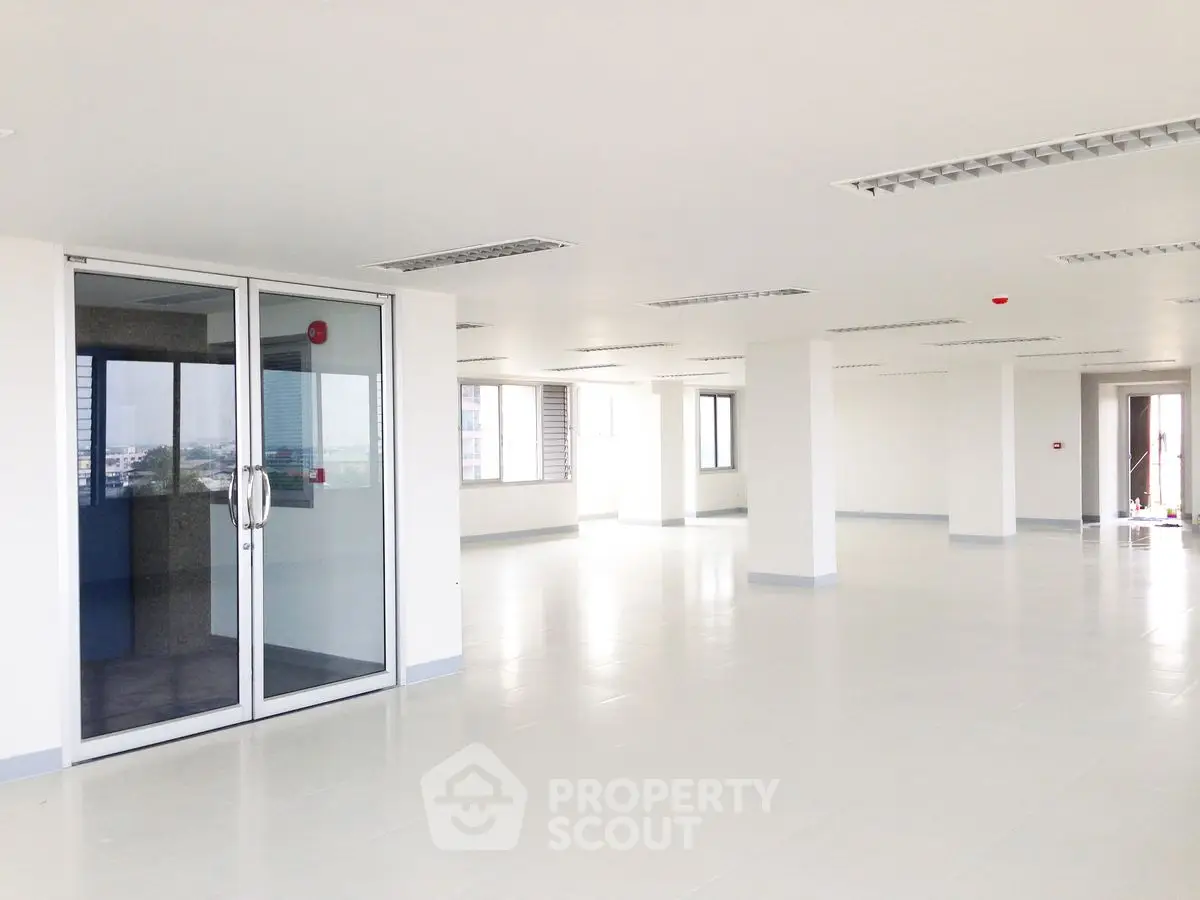 Spacious open-plan office space with large windows and modern lighting.