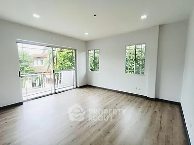Spacious living room with large windows and balcony access, featuring elegant wood flooring.