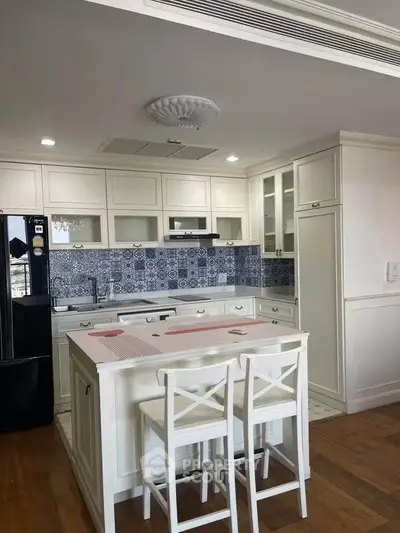 Charming kitchen with white cabinetry and stylish blue backsplash, featuring a cozy breakfast bar and modern appliances.