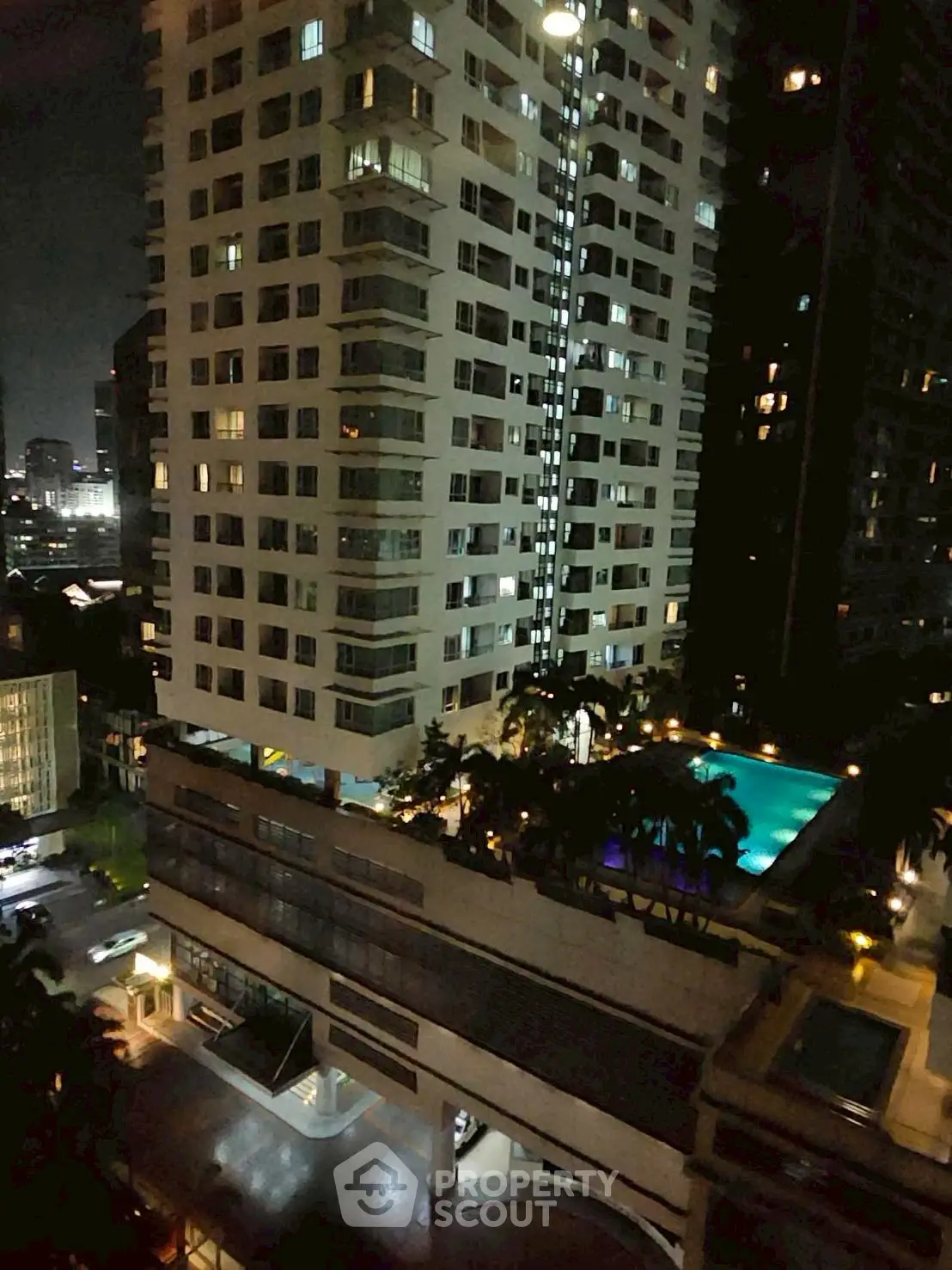Stunning night view of a high-rise building with illuminated pool area and cityscape backdrop.