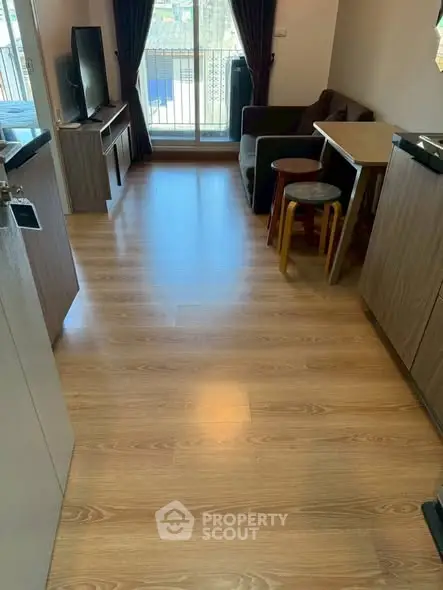 Cozy living room with wooden flooring and balcony access, perfect for relaxation.