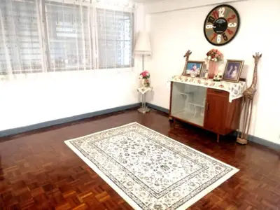 Charming living room with parquet flooring and vintage decor, featuring a stylish clock and elegant sideboard.