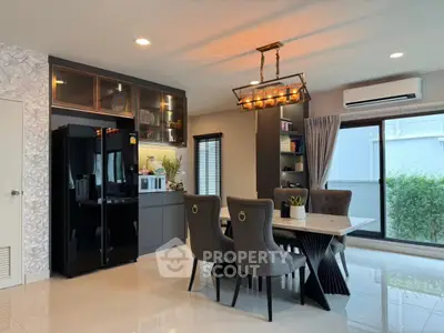 Modern dining area with elegant chandelier and sleek black appliances