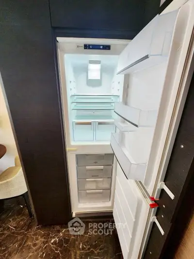 Modern kitchen with open fridge showcasing spacious interior and sleek design.