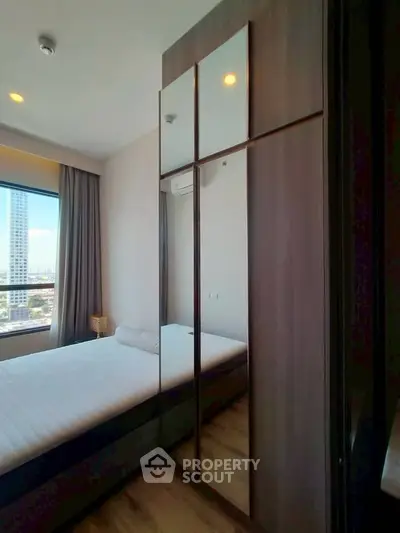 Modern bedroom with large window and mirrored wardrobe in urban apartment