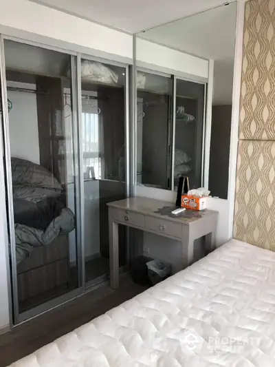 Modern bedroom with mirrored closet and stylish vanity in a cozy apartment.