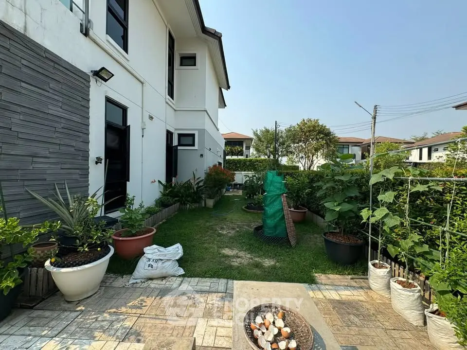 Charming garden view of modern house exterior with lush greenery and cozy patio area.