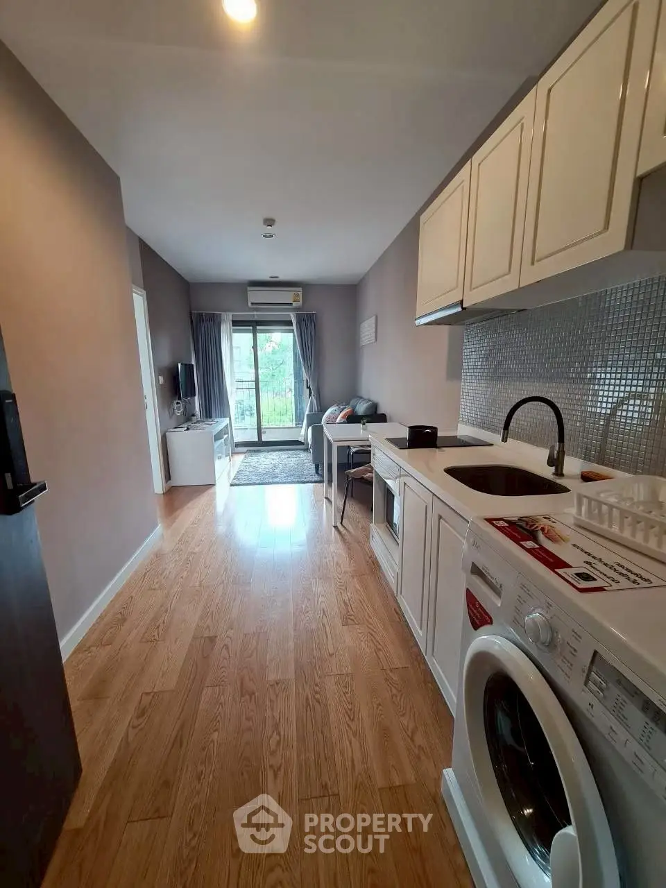 Modern apartment interior with open kitchen and living area, featuring hardwood floors and natural light.