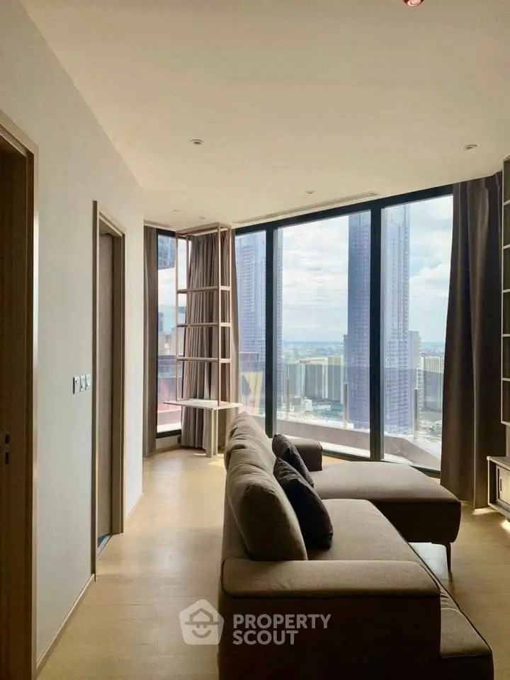 Modern living room with floor-to-ceiling windows offering stunning city views and stylish furnishings.