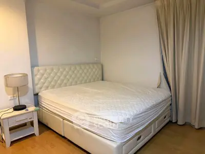 Spacious bedroom with elegant white bed and stylish lamp, perfect for relaxation and comfort.
