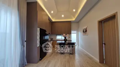 Modern kitchen with high ceiling and elegant lighting, featuring a central island and sleek cabinetry.