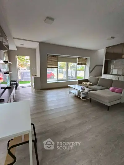 Modern living room with large window and stylish furniture in a bright, open space.