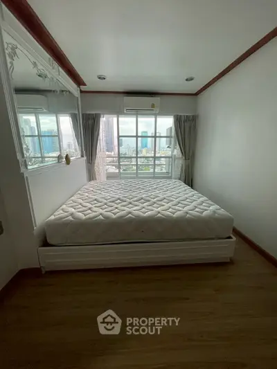 Cozy bedroom with city view, featuring a comfortable bed and large window for natural light.