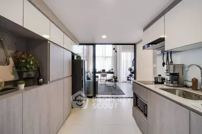 Modern kitchen with sleek cabinetry and open layout leading to dining area.