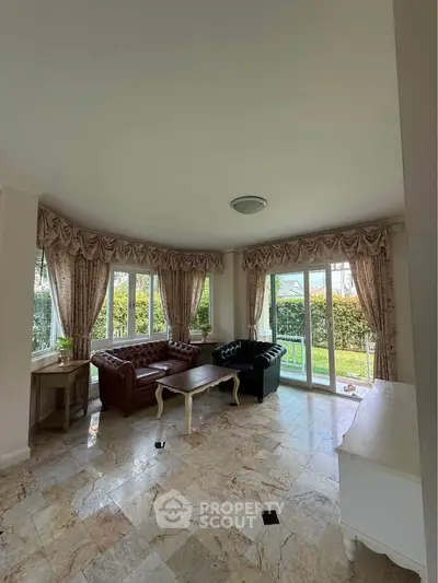 Elegant living room with large windows and garden view, featuring classic furniture and marble flooring.
