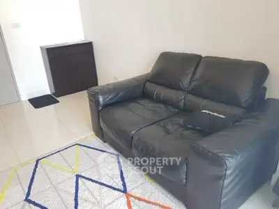 Cozy living room with black leather sofa and modern geometric rug