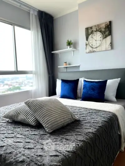Modern bedroom with stylish decor and large window offering city views.