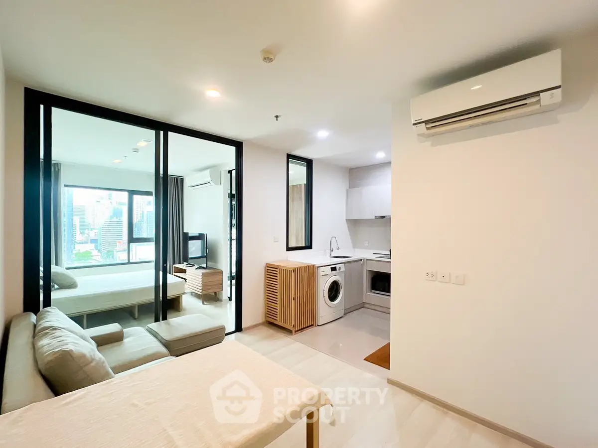 Modern open-plan apartment with city view, featuring a cozy living area, sleek kitchen, and spacious bedroom.