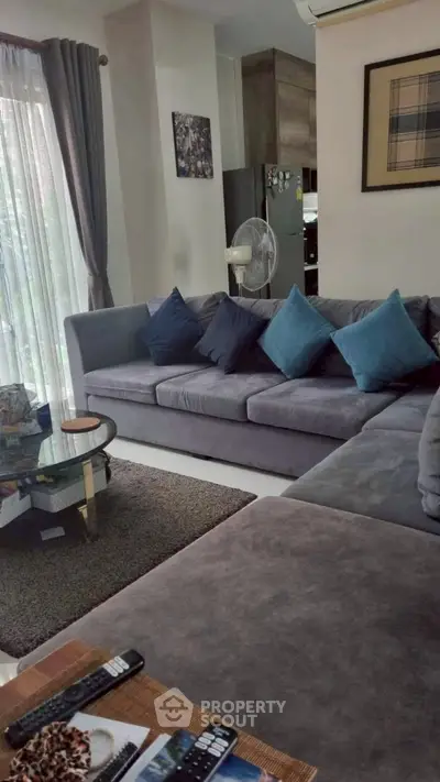 Spacious living room with modern gray sofa and stylish decor, perfect for relaxation and entertainment.