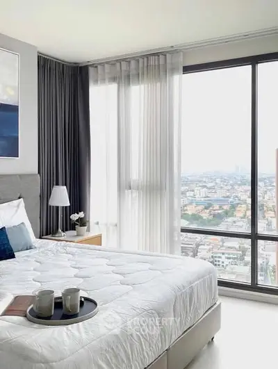 Modern bedroom with large windows offering stunning city views and elegant decor.