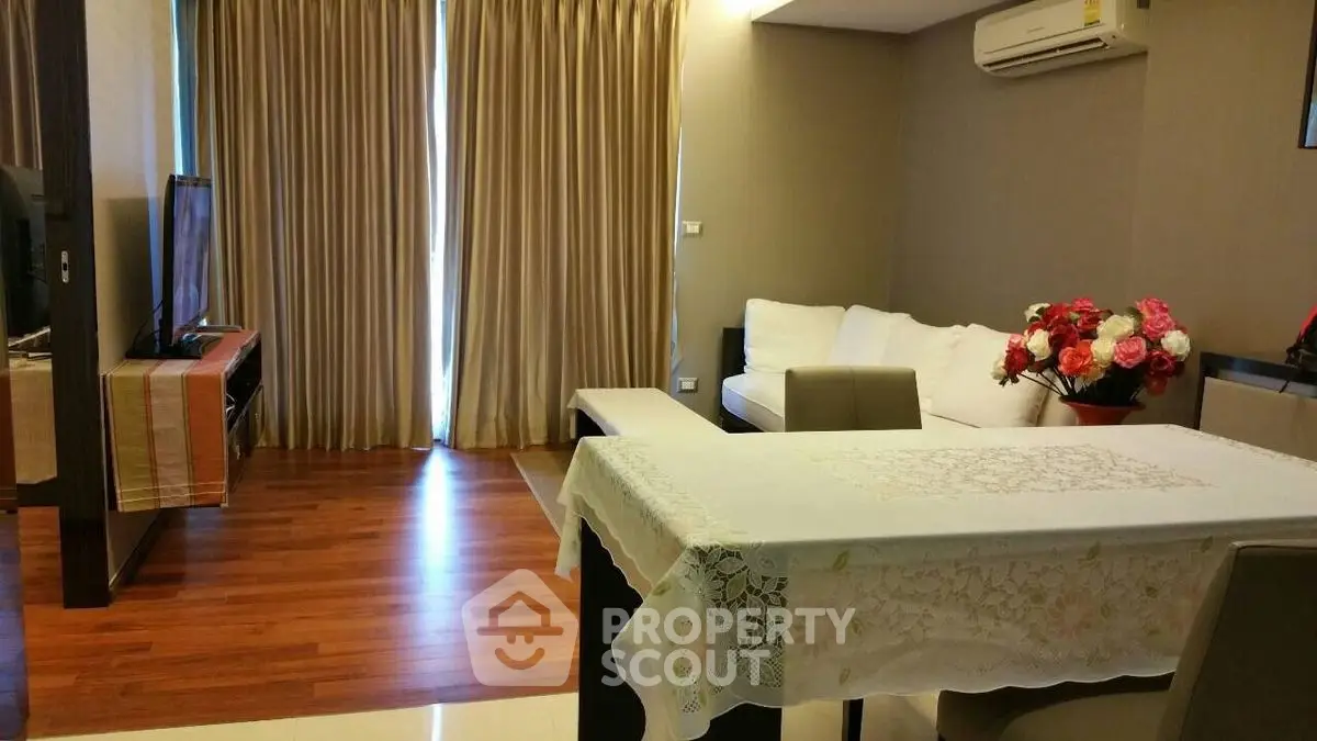 Cozy living room with wooden flooring and elegant decor, featuring a comfortable sofa and modern TV setup.