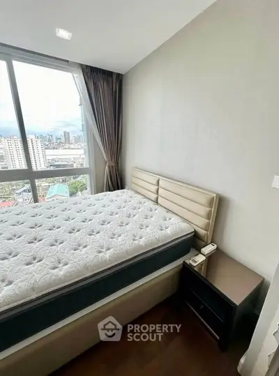 Modern bedroom with city view, featuring a comfortable bed and stylish decor.