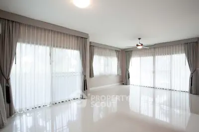 Spacious and bright living room with large windows and elegant curtains